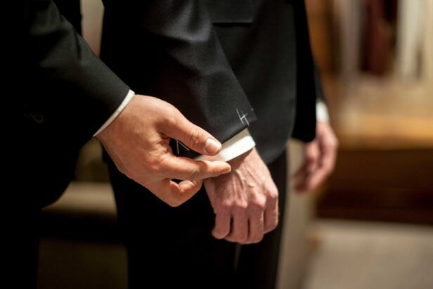 A tailor adjusts the sleeve length of a wedding suit