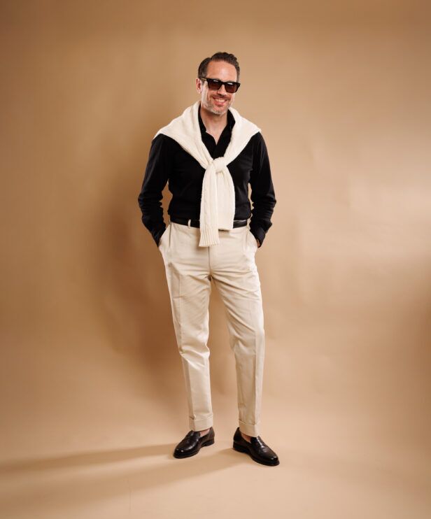 Black penny loafers styled with cream sweater and stone trousers for old money modern look