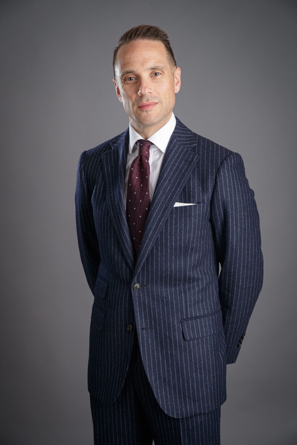 Custom-tailored navy suit with narrow chalk stripe detailing.