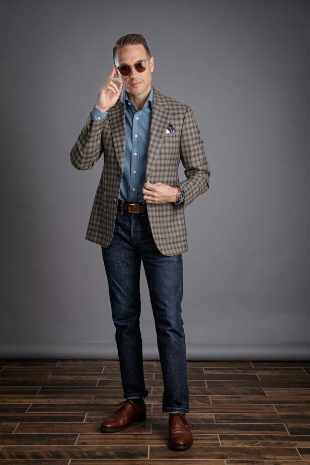 A gun club check blazer worn with a denim dress shirt and blue jeans