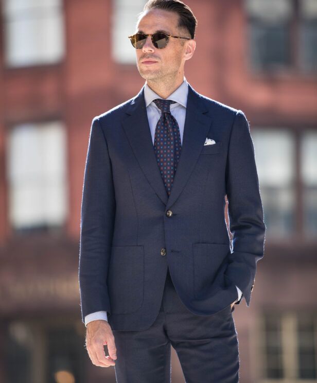 Navy hopsack suit with patch pockets, blue shirt and burgundy medallion tie, on a city street