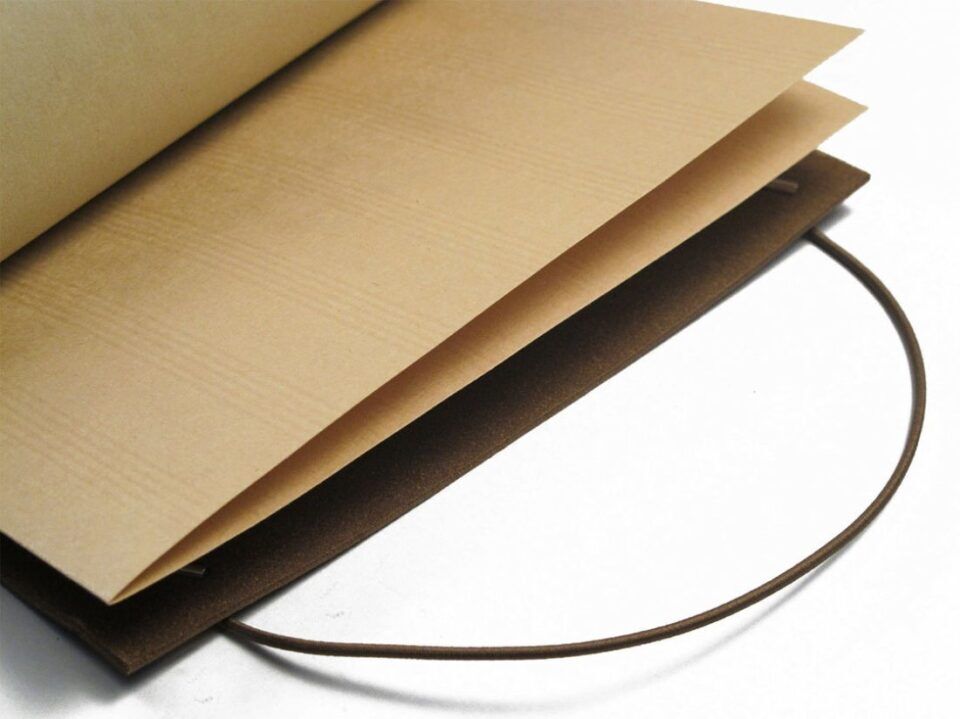 Kraft paper notebook with brown cover and elastic cord closure, open, a close-up detail