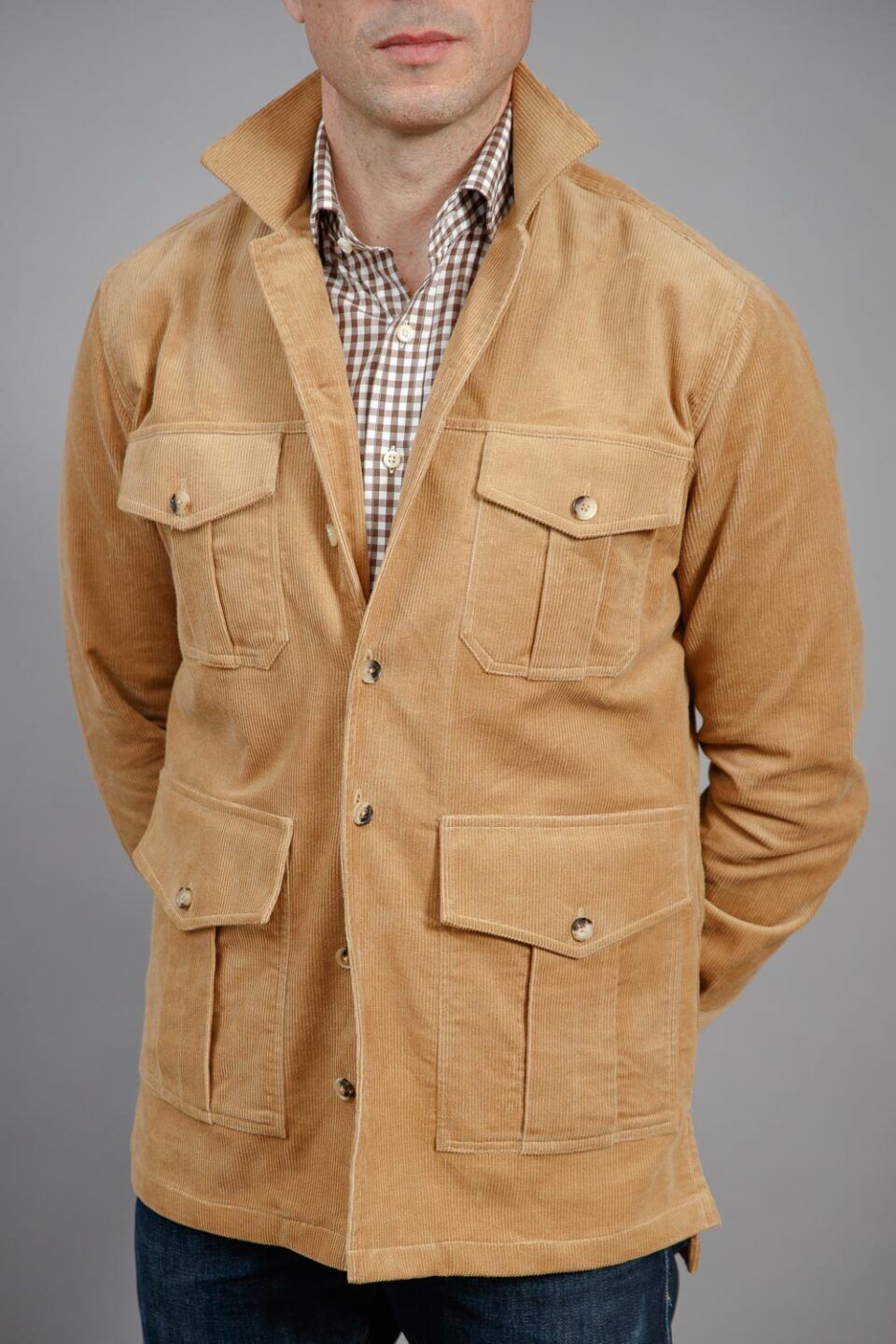 Tan corduroy four-pocket safari jacket with brown gingham shirt and jeans, worn by a model