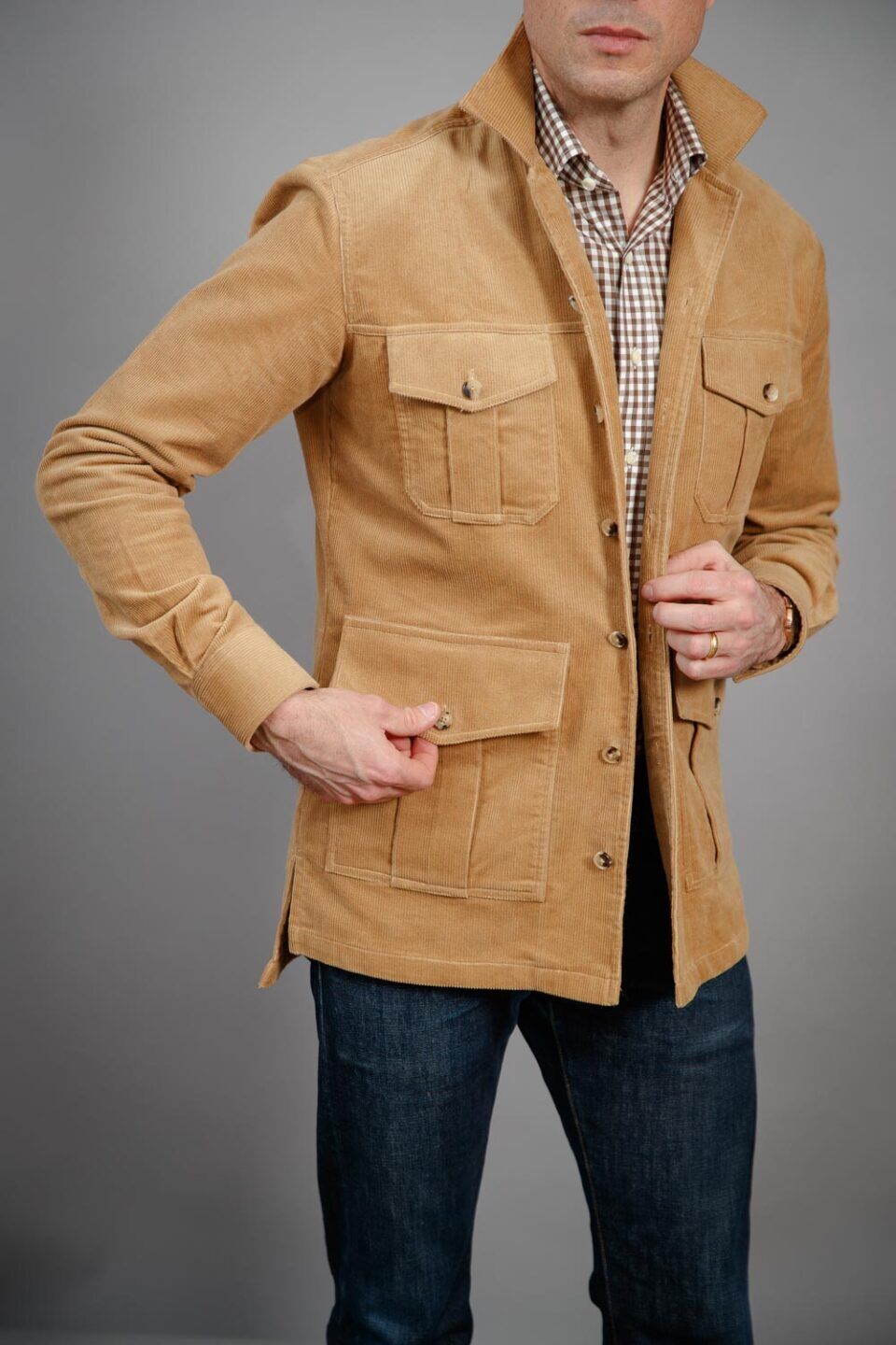 Tan corduroy four-pocket safari jacket with brown gingham shirt and blue jeans, worn by a model