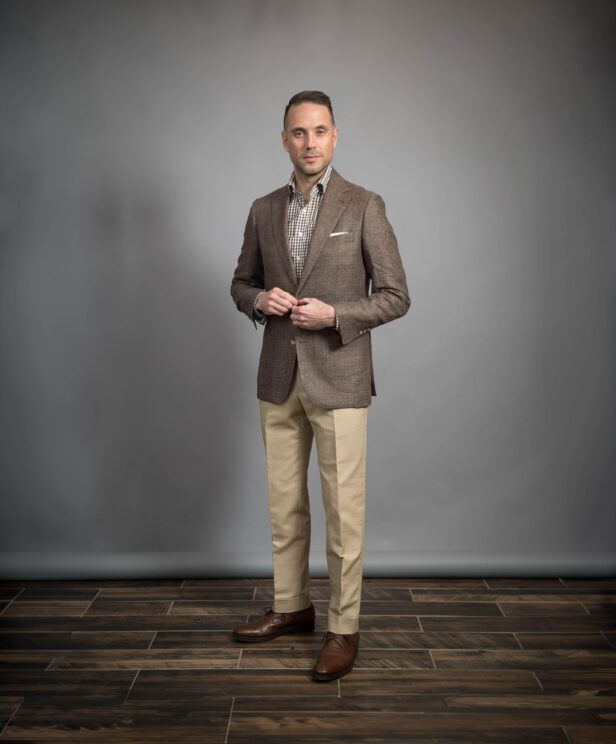 Brown linen sport coat with brown gingham shirt, khaki chinos and brown derbies, worn by a model