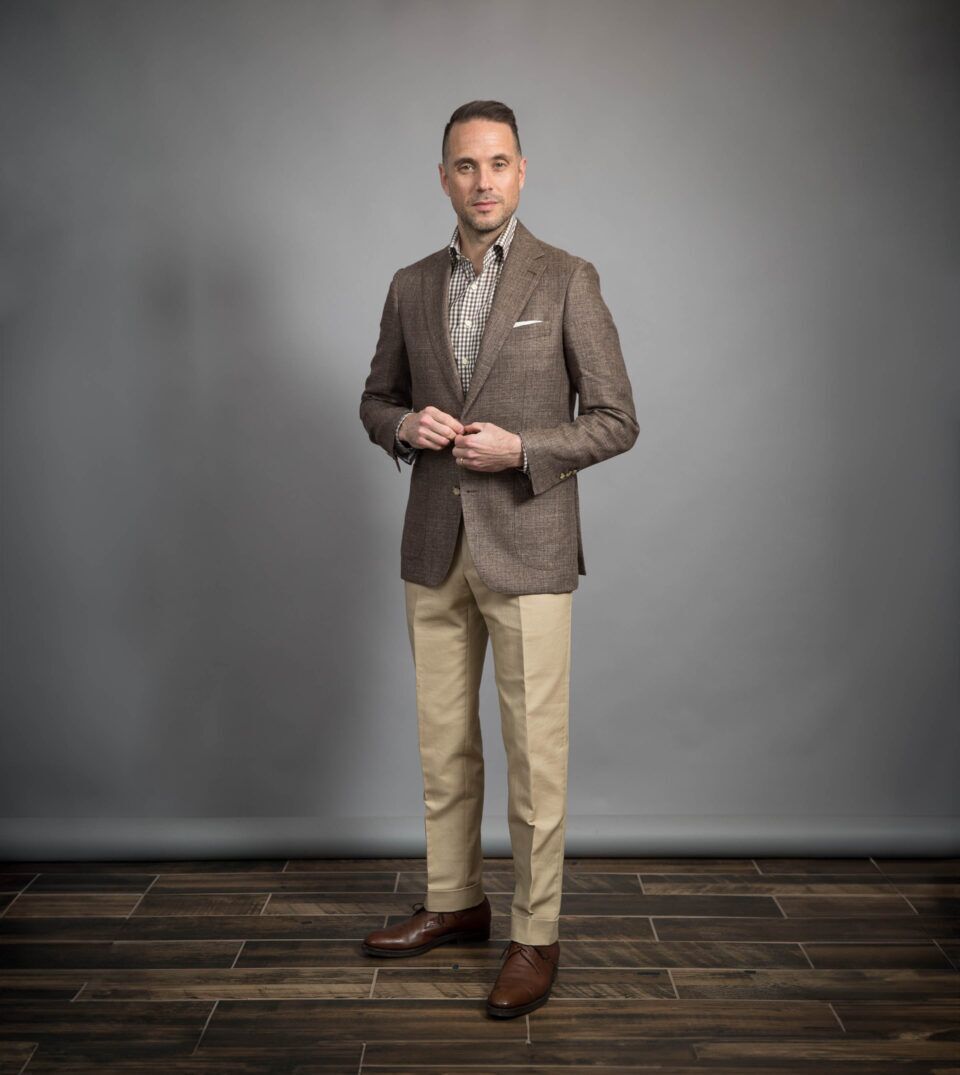 Brown linen sport coat with brown gingham shirt, khaki chinos and brown derbies, worn by a model
