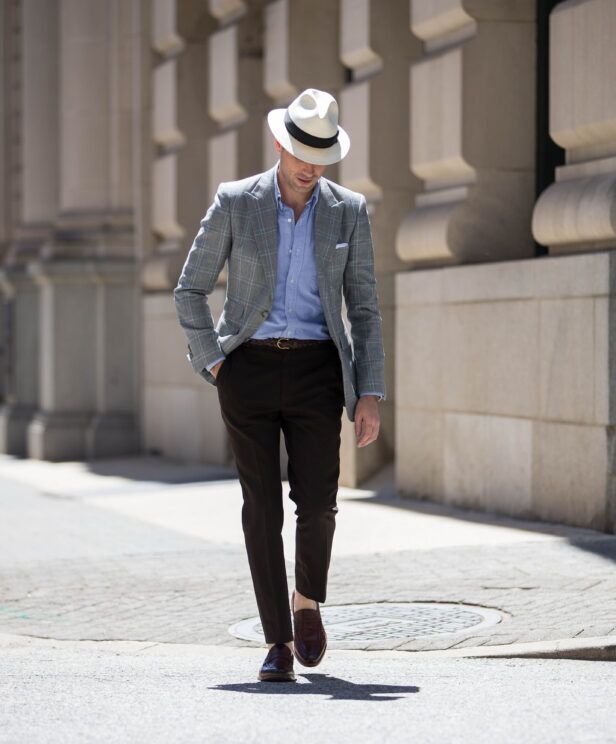 Grey windowpane plaid sport coat with blue oxford shirt, brown trousers and loafers, worn by a model on a city street