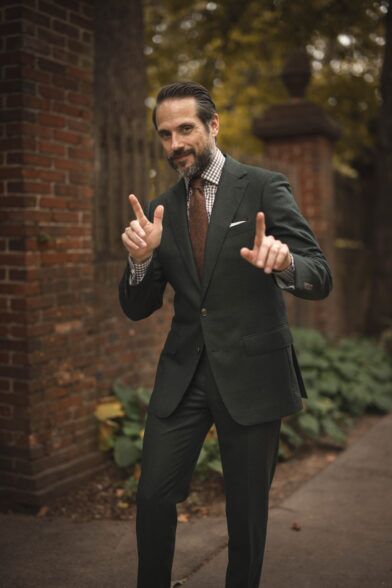 Forest green flannel suit with brown gingham shirt, brown knit tie and white pocket square, worn by a model