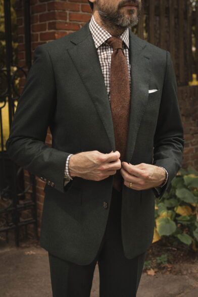 Forest green flannel suit with peak lapels, brown gingham shirt and rust wool tie, worn by a model