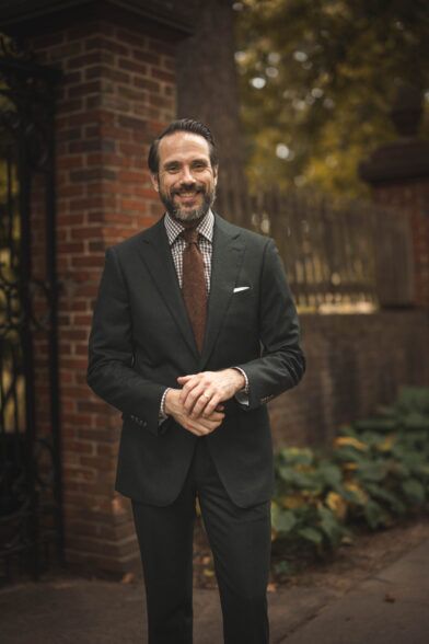 Forest green flannel suit with brown checked shirt, rust knit tie and white pocket square, worn by a model