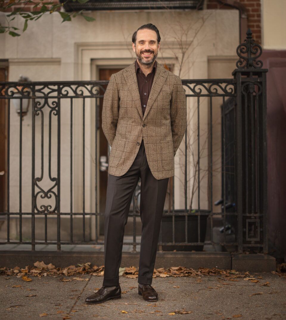Brown glen plaid wool sport coat with burgundy knit polo, dark brown trousers and loafers, worn by a model
