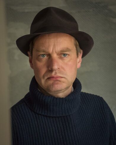 Dark brown felt fedora with grosgrain band, worn with a navy ribbed turtleneck sweater by a model