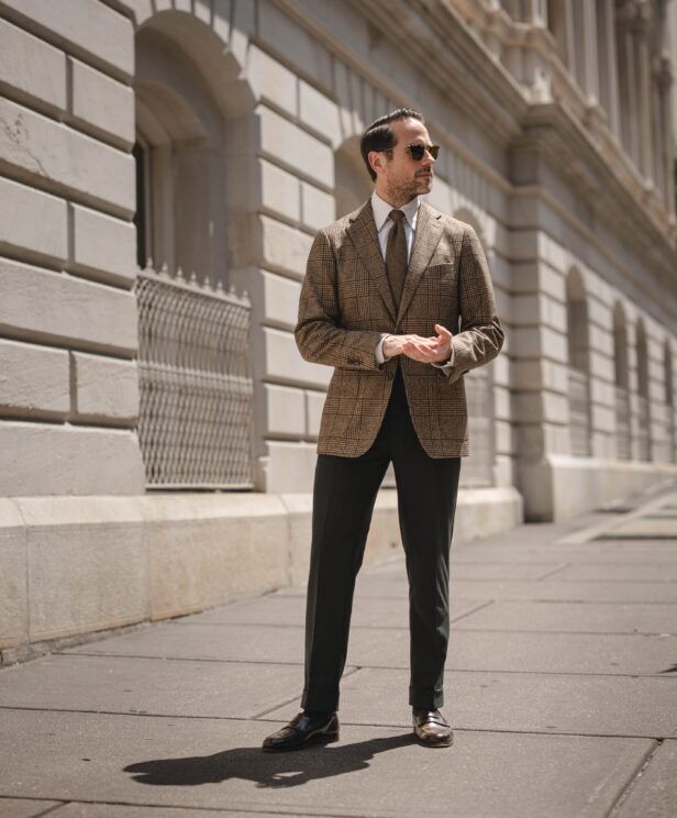Brown glen check wool sport coat with white shirt, olive tie and dark green trousers, worn by a model on a city street