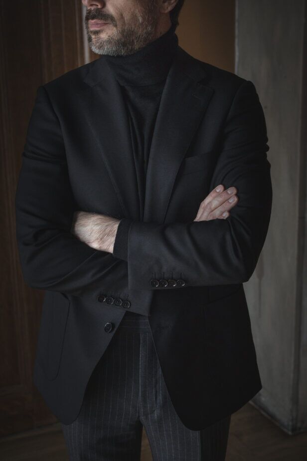 Black basket weave wool sport coat with black turtleneck and charcoal pinstripe trousers, worn by a model