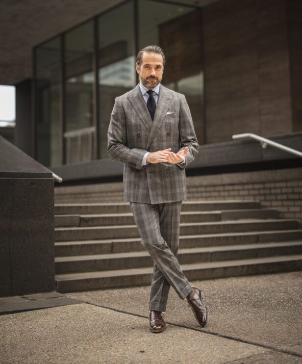 Grey plaid flannel double-breasted suit with blue shirt, navy tie and brown oxfords, worn by a model