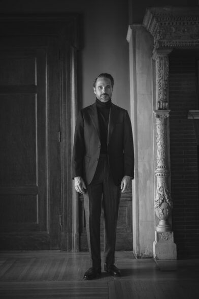 Black basket weave sport coat with dark turtleneck and pinstripe trousers, worn by a model