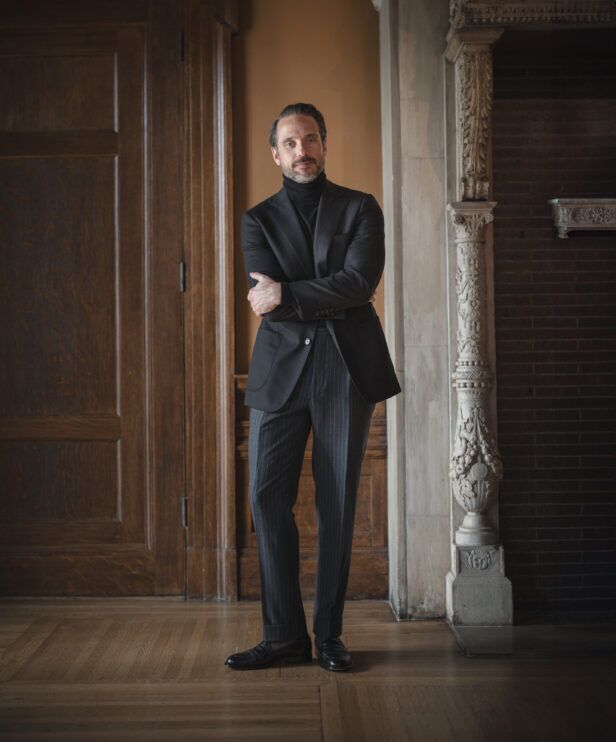 Black basket weave sport coat with black turtleneck, grey pinstripe trousers and black loafers, worn by a model