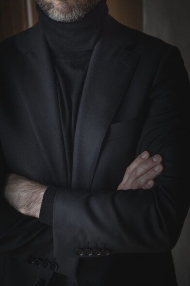Black basket weave wool sport coat with notch lapels over a black turtleneck, worn by a model