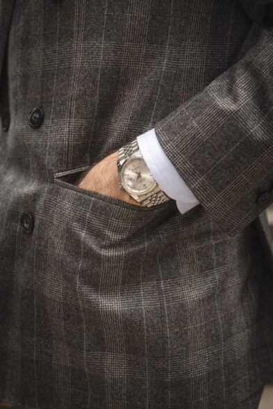 Grey glen plaid flannel double-breasted jacket with jetted pocket and white shirt cuff, a close-up detail