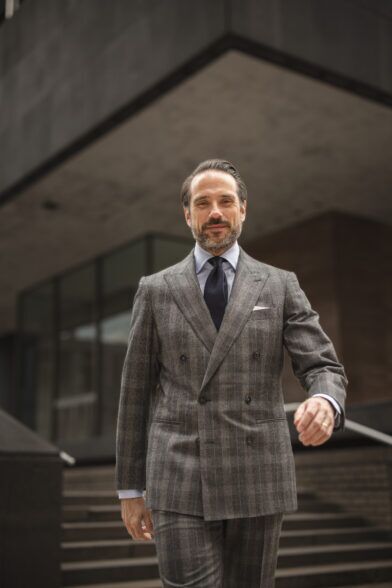 Grey plaid flannel double-breasted suit with light blue shirt and navy grenadine tie, worn by a model