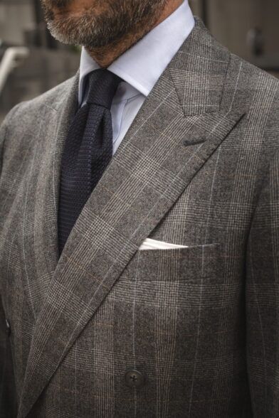 Grey Prince of Wales check flannel double-breasted suit with navy grenadine tie, a close-up