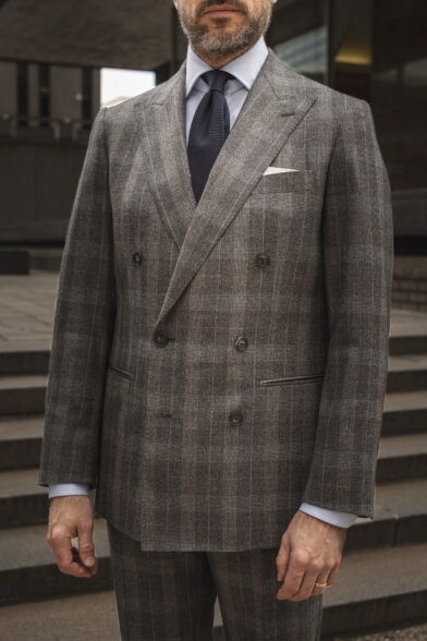 Grey glen plaid flannel double-breasted suit with light blue shirt and navy grenadine tie, on a model