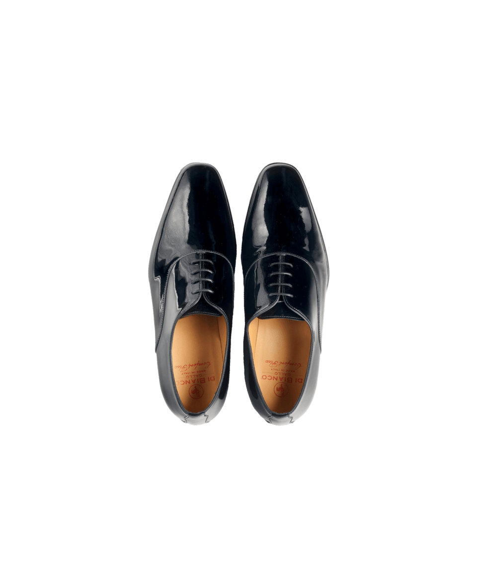 Black patent leather wholecut oxford shoes with tan leather insoles, overhead flat lay
