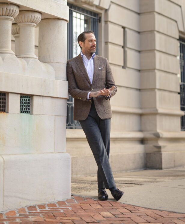 Brown textured wool-silk sport coat with blue shirt, white pocket square and grey trousers, worn by a model outdoors