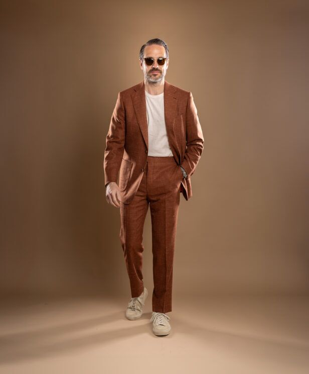 Terra cotta textured linen-blend suit with cream t-shirt and off-white sneakers, worn by a model