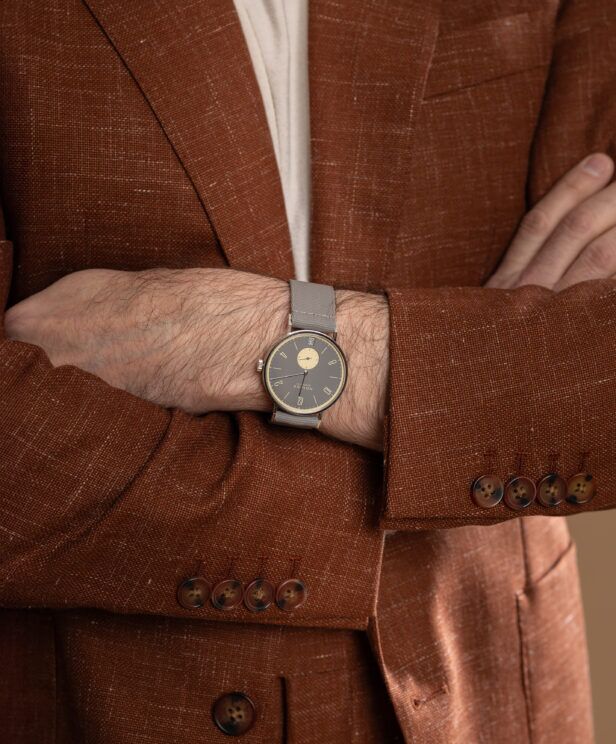 Terracotta linen sport coat with horn cuff buttons and grey-strap watch, a close-up detail on a model