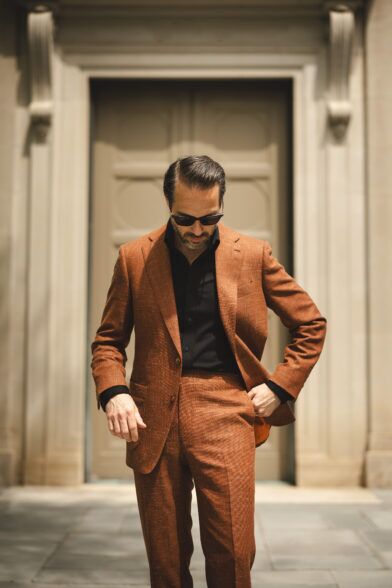 Terracotta textured linen-blend suit with black shirt and sunglasses, worn by a model on a city street