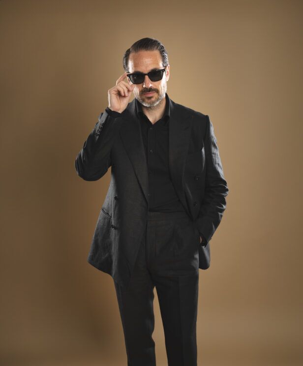 Black linen double-breasted suit with peak lapels and black shirt, worn by a model