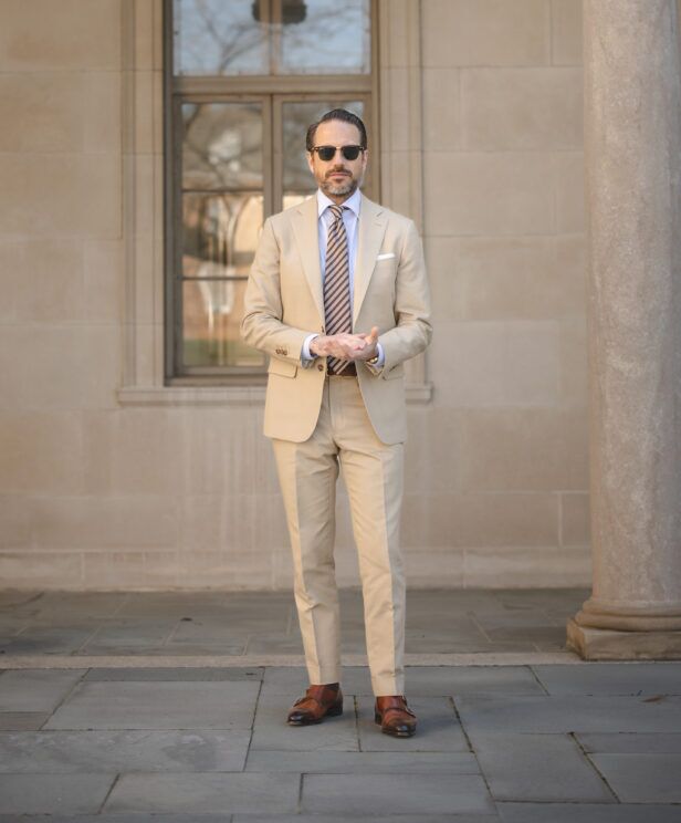Khaki cotton suit with blue shirt, brown striped tie and tan monk strap shoes, worn by a model