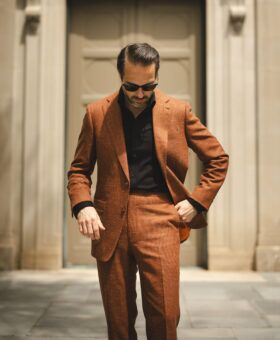 Terracotta linen-blend single-breasted suit with black knit polo shirt, worn by a model on a city street
