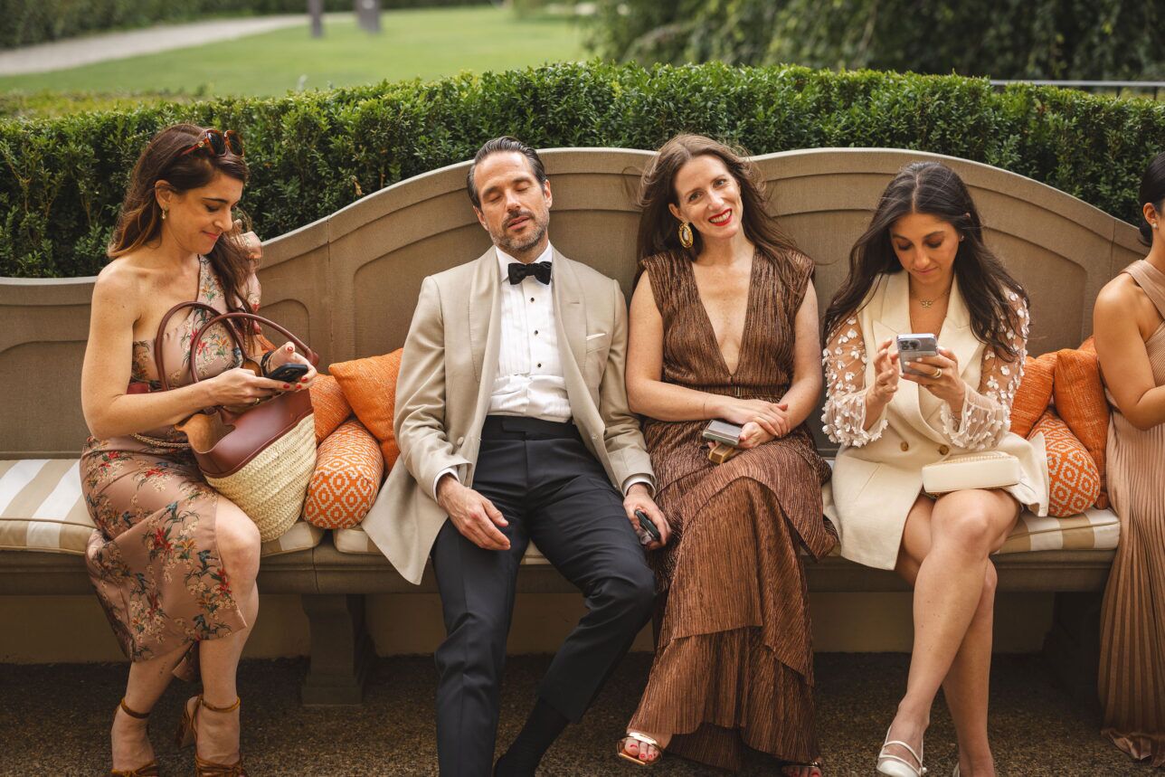 Ivory dinner jacket with black bow tie, pique stud front shirt and black trousers, worn on a garden bench