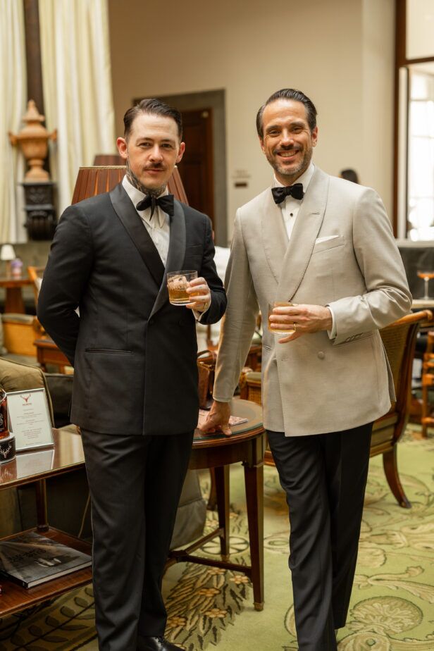 Black shawl collar dinner jacket and cream double-breasted dinner jacket, worn by two men at a cocktail event