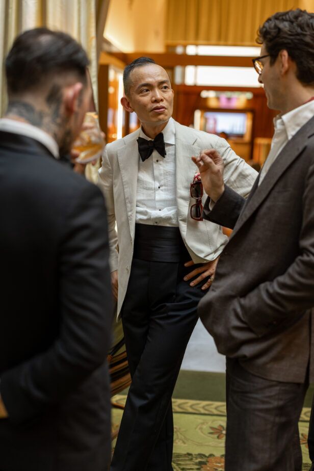 Cream dinner jacket with black bow tie, pleated dress shirt, cummerbund and navy trousers, worn at a cocktail event