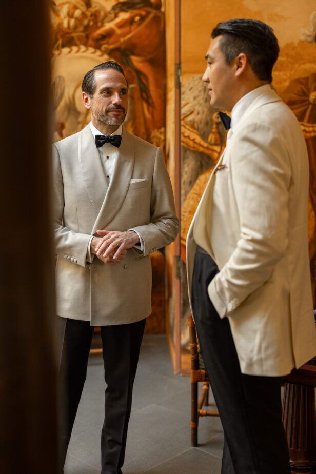Ivory shawl collar dinner jackets with black bow ties and black trousers, worn by two men at an evening event