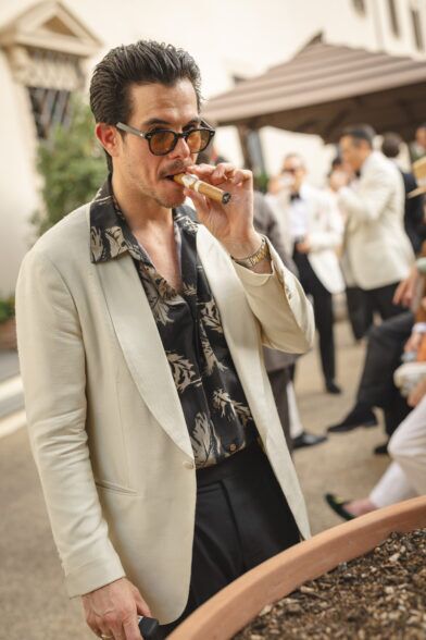 Cream shawl collar dinner jacket with black and tan floral camp shirt and black trousers, worn at an outdoor cocktail event