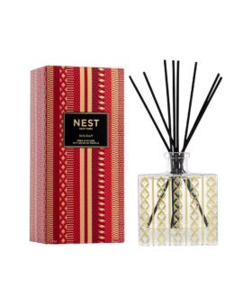 Nest New York Holiday reed diffuser in a gold-patterned glass bottle beside its red box