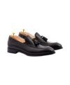 Pair of black leather tassel loafers with shoe trees, angled product view
