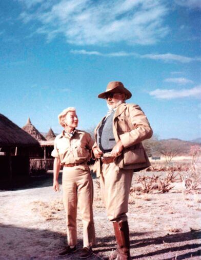 Tan safari jacket over a waistcoat with a bush hat, worn beside a woman in khaki