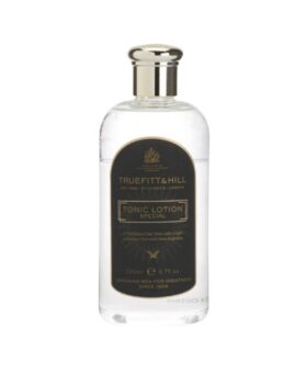 Clear glass bottle of hair tonic lotion with a silver cap and black label