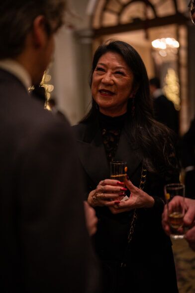 Black tailored jacket over a lace top, worn by a guest holding a cocktail
