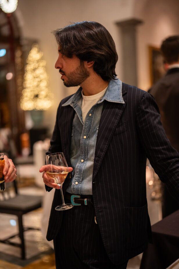 Navy pinstripe suit over a chambray shirt with a turquoise belt, worn by a guest