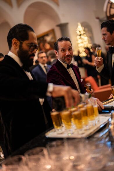 Burgundy velvet dinner jacket with bow tie, worn by a guest serving drinks at the bar