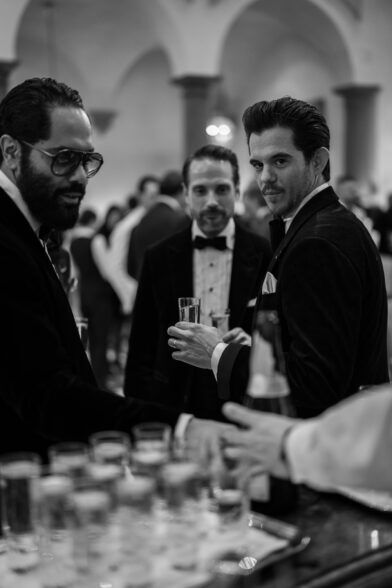 Black velvet dinner jackets worn by three guests at the bar, a black and white photograph