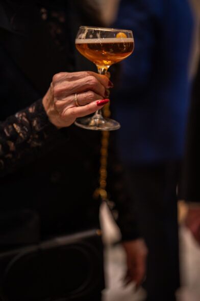 Coupe of champagne held by a guest in a beaded black jacket