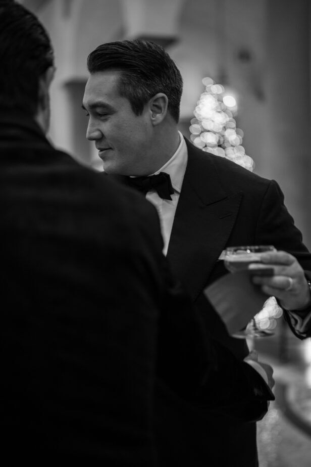 Black peak lapel dinner jacket with bow tie, worn by a guest in a black and white photograph