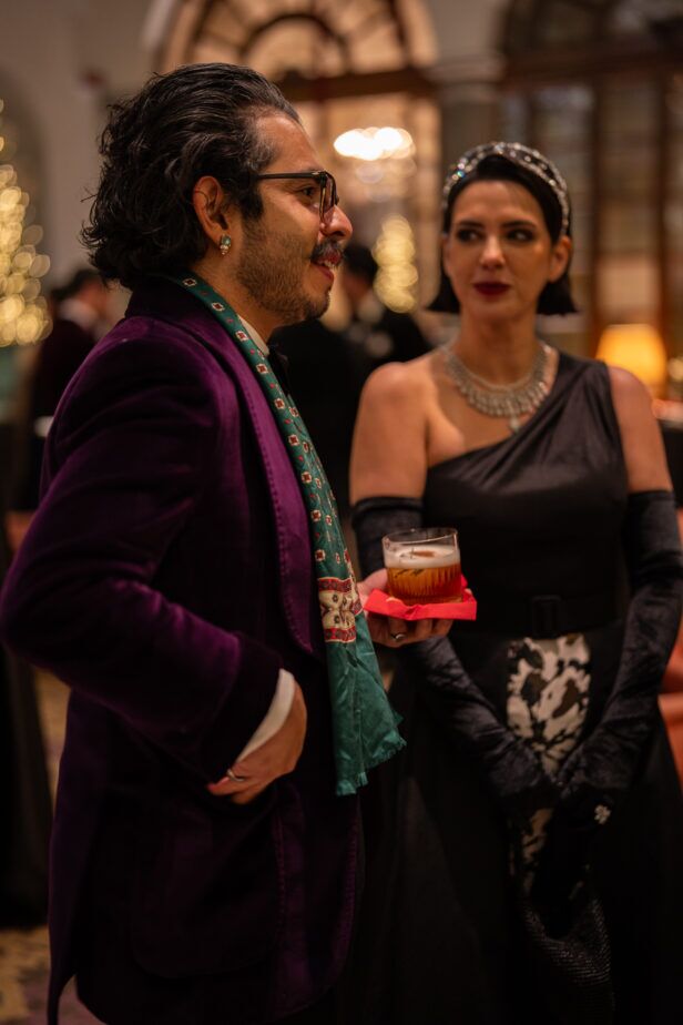 Purple velvet dinner jacket with a green printed scarf, worn beside a woman in black